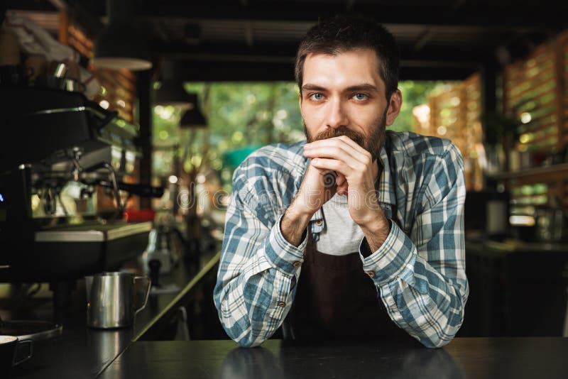 微笑对照相机的英俊的barista人画象,当工作在室外时街道的咖啡馆或的咖啡馆 图库摄影