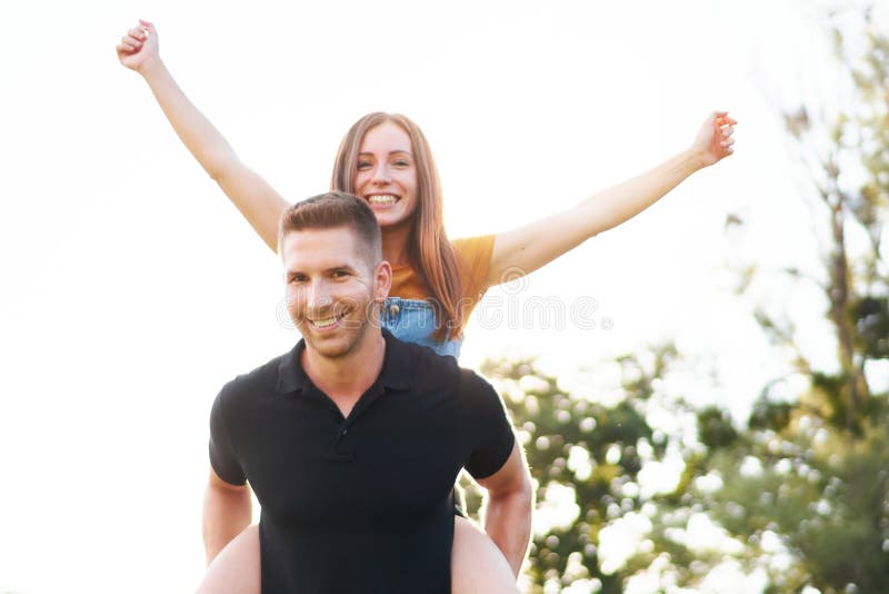 快乐的千禧一代新人情侣，在一起玩，喜欢户外背光暖色调的搭车概念 库存照片