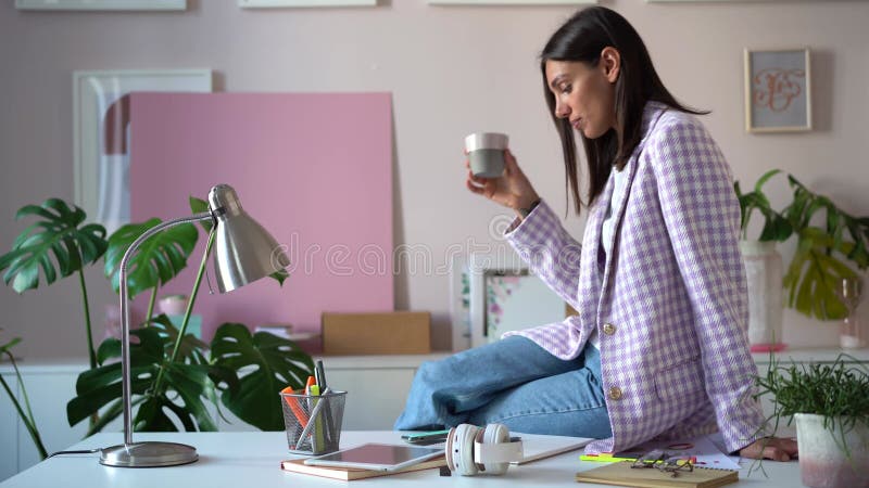 快乐的女商人喝咖啡，当站在办公室附近时表. 有一杯的想法的妇女热饮料 影视素材