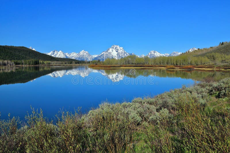 The sheer peaks of the Grand Teton Range and Mount Moran are reflected in the still waters of the Oxbow Bend of the Snake River, Grand Teton National Park, Rocky Mountains, Wyoming, USA. The sheer peaks of the Grand Teton Range and Mount Moran are reflected in the still waters of the Oxbow Bend of the Snake River, Grand Teton National Park, Rocky Mountains, Wyoming, USA.