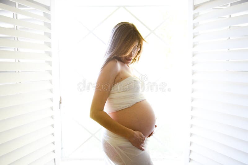 怀孕的腹部. 婴孩腹部前面她看起来的怀孕的视窗妇女