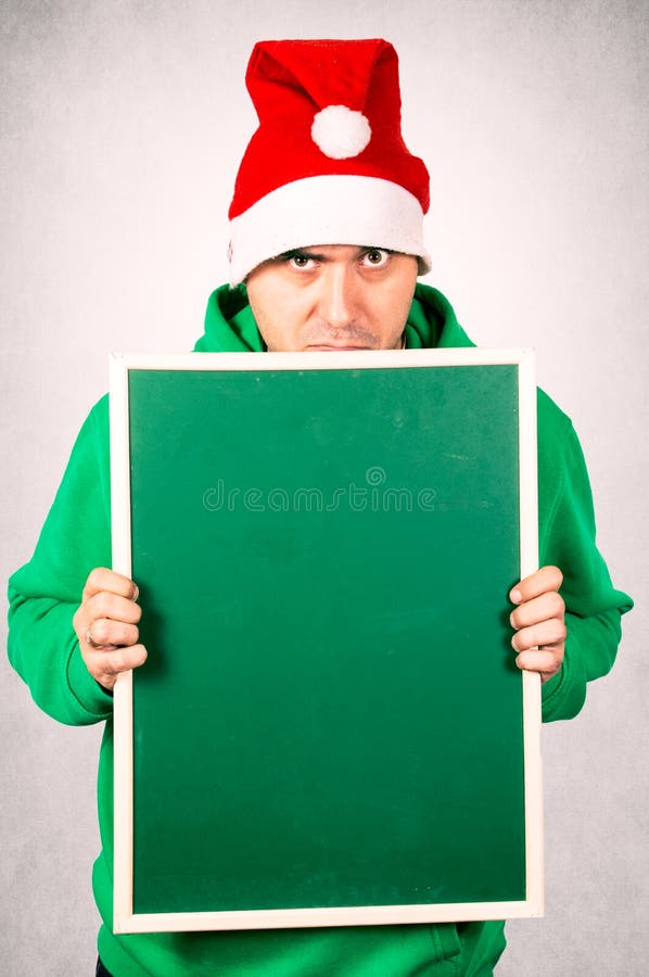 Angry Santa holding blank green chalk board. Angry Santa holding blank green chalk board