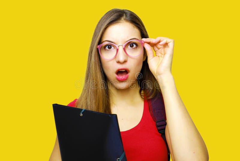 惊奇的美丽的学生女孩 在黄色背景的年轻震惊学生妇女藏品文件夹 免版税库存图片 惊奇的美丽的学生女孩 在黄色背景的年轻震惊学生妇女藏品文件夹 免版税库存图片