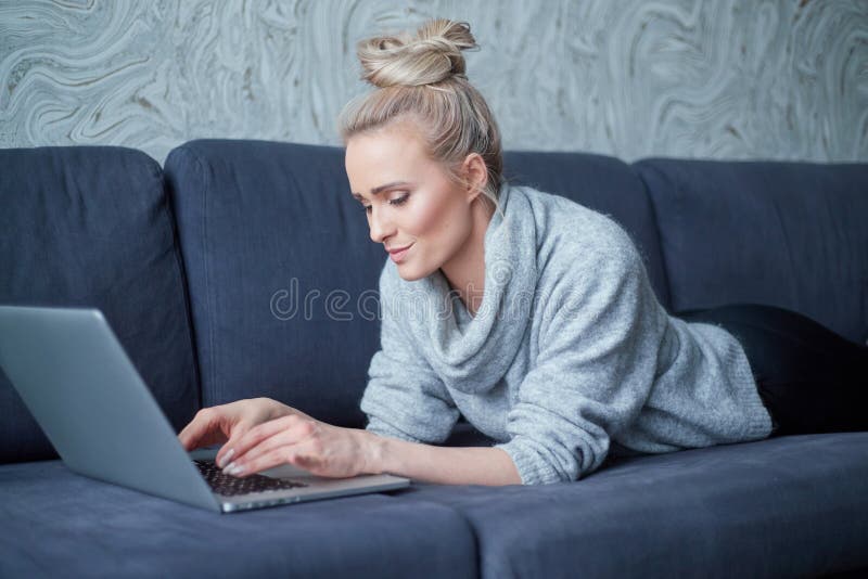 愉快白肤金å‘妇女说谎有倾å‘在沙å‘å’Œç ”ç©¶æ‰‹æç”µè„‘ 库存照片 愉快白肤金å‘妇女说谎有倾å‘在沙å‘å’Œç ”ç©¶æ‰‹æç”µè„‘ 库存照片
