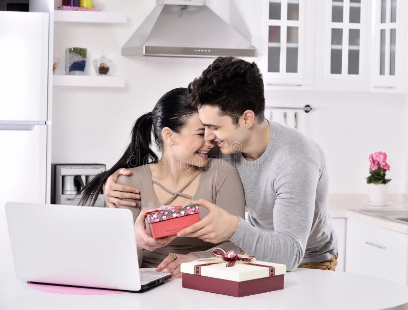 Happy young couple with gift boxes. in the kitchen, in home. Happy young couple with gift boxes. in the kitchen, in home.