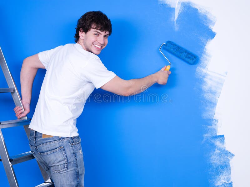 Handsome young man with happy smile painting the wall. Handsome young man with happy smile painting the wall