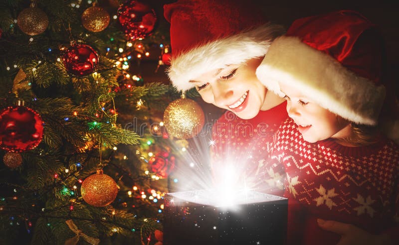 Happy family mother and child daughter with magical gift from the Christmas tree. Happy family mother and child daughter with magical gift from the Christmas tree