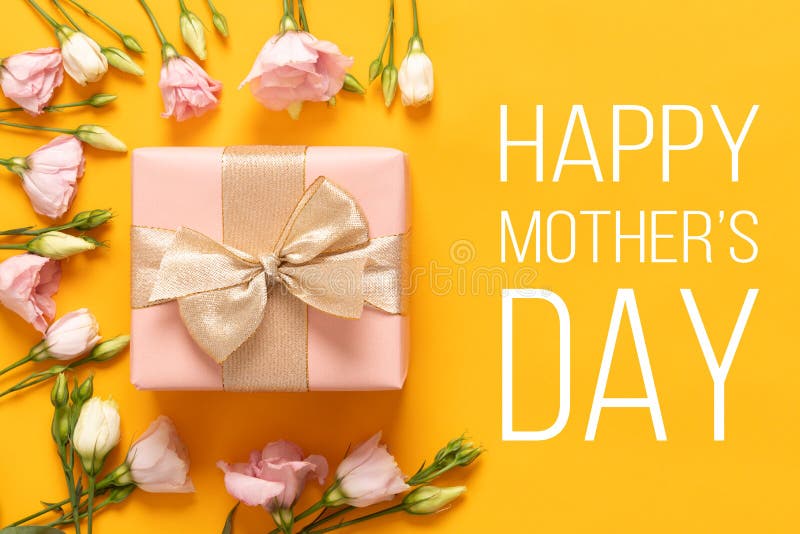 Happy Mother`s Day Background. Bright Yellow and Pastel Pink Colored Mother Day Background. Flat lay greeting card with beautiful gift box and pink lisianthus flowers. Happy Mother`s Day Background. Bright Yellow and Pastel Pink Colored Mother Day Background. Flat lay greeting card with beautiful gift box and pink lisianthus flowers