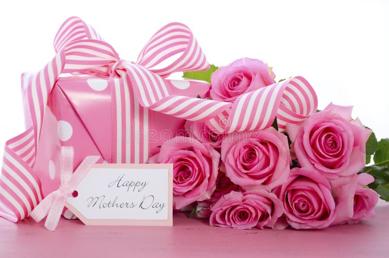 Happy Mothers Day pink polka dot gift with pink and white stripe ribbon and gift tag on vintage pink wood table. Happy Mothers Day pink polka dot gift with pink and white stripe ribbon and gift tag on vintage pink wood table.