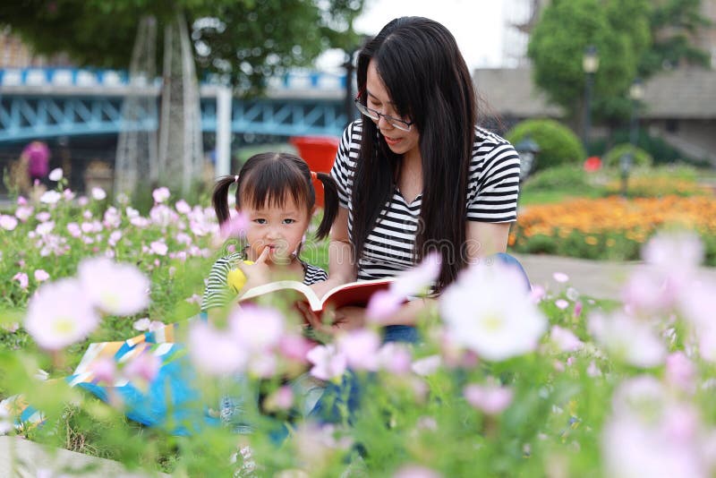 愉快的矮小的逗人喜爱的女婴微笑和笑读与母亲的书,妈妈讲故事给他的夏天公园愉快的家庭的女儿 库存图片 愉快的矮小的逗人喜爱的女婴微笑和笑读与母亲的书,妈妈讲故事给他的夏天公园愉快的家庭的女儿 库存图片