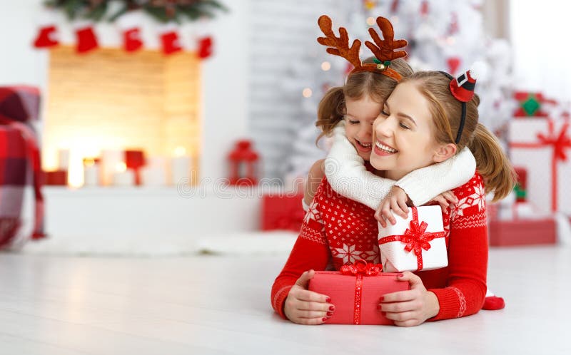 Happy family mother and daughter giving christmas gift and embracing. Happy family mother and daughter giving christmas gift and embracing