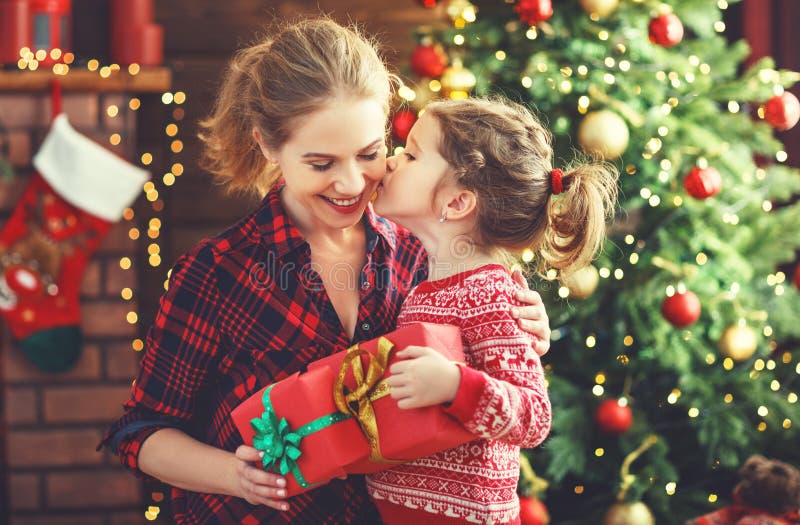 Happy family mother and daughter giving christmas gift and embracing. Happy family mother and daughter giving christmas gift and embracing