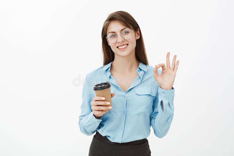 成交优良在我们的手,一切里 玻璃和蓝色女衬衫的友好的迷人的女实业家,显示好或好 免版税库存照片 成交优良在我们的手,一切里 玻璃和蓝色女衬衫的友好的迷人的女实业家,显示好或好 免版税库存照片
