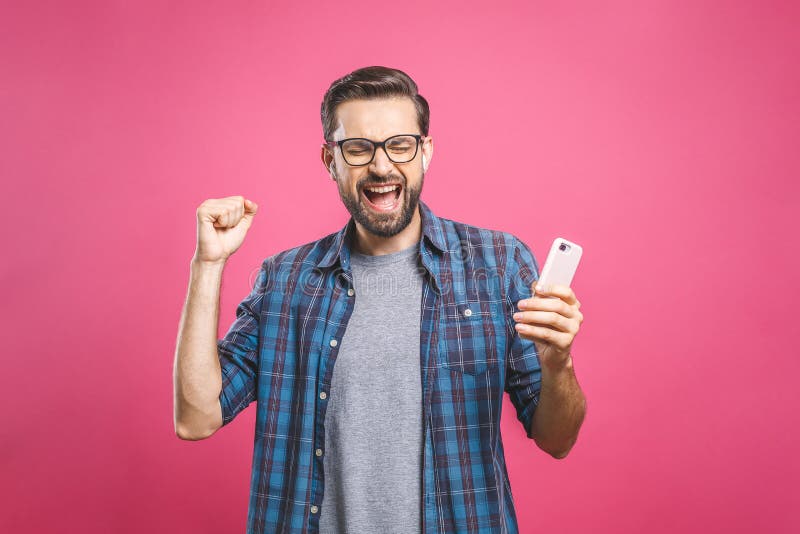 I`m a winner! Happy man holding smartphone and celebrating his success isolated over pink background. I`m a winner! Happy man holding smartphone and celebrating his success isolated over pink background