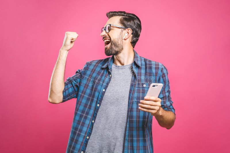 I`m a winner! Happy man holding smartphone and celebrating his success isolated over pink background. I`m a winner! Happy man holding smartphone and celebrating his success isolated over pink background