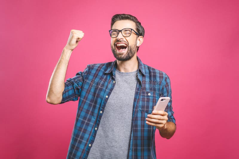 I`m a winner! Happy man holding smartphone and celebrating his success isolated over pink background. I`m a winner! Happy man holding smartphone and celebrating his success isolated over pink background