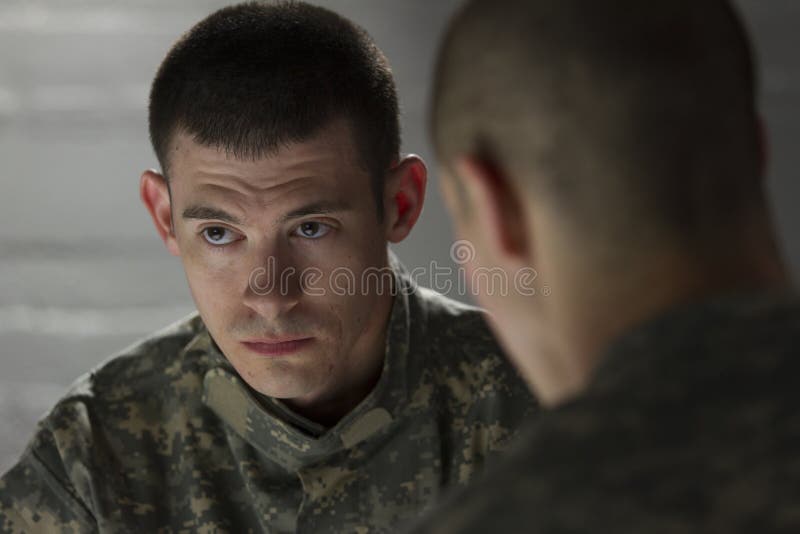 Somber looking soldier being consoled by peer in dark room. Somber looking soldier being consoled by peer in dark room