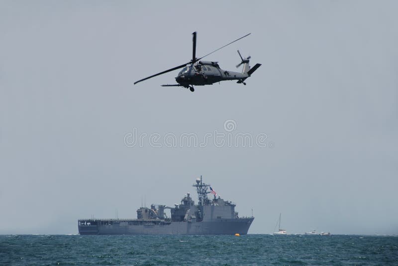 Modern Navy helicopter hovering over a battleship out in the ocean. Modern Navy helicopter hovering over a battleship out in the ocean