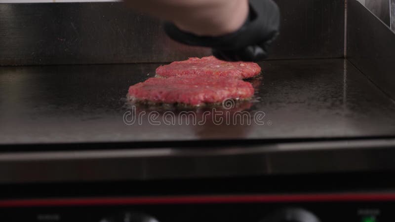 戴手套的厨师在餐馆厨房把汉堡饼放在烤箱里. 股票录像