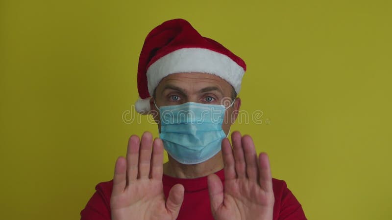 戴着圣诞帽和面具的男子拒绝，并摆出过手示意禁止.