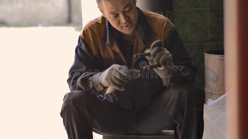 戴着手套和工作服的亚洲人,正在修理车库里汽车的一个备用部分 股票视频