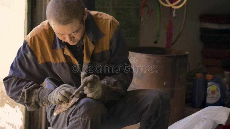 戴着手套和工作服的亚洲人,正在修理车库里汽车的一个备用部分 股票视频