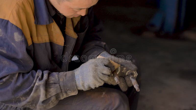 戴着手套和工作服的亚洲人,正在修理车库里汽车的一个备用部分 股票录像