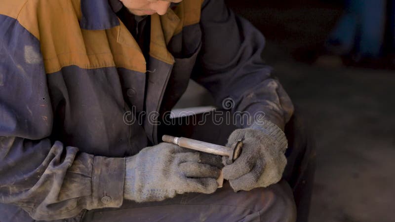 戴着手套和工作服的亚洲人,正在修理车库里汽车的一个备用部分 影视素材