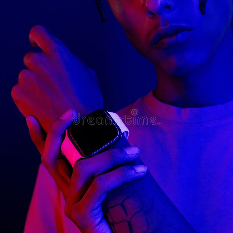 A man wearing a black wristwatch against a vibrant neon background of pink and blue. A man wearing a black wristwatch against a vibrant neon background of pink and blue