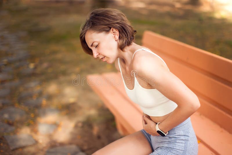 户外腹痛运动妇女. 健康保健与医学概念 免版税库存图片