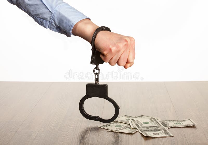 Hands in handcuffs and money on the table; white background. Hands in handcuffs and money on the table; white background