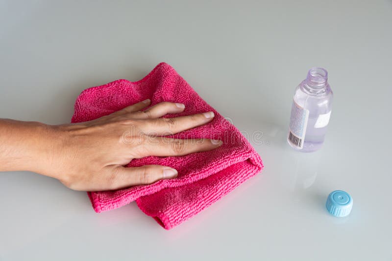 Hand holding a cloth next to a bottle of gel alcohol for desinfection of a surface to prevent corona vÃ Â­rus covid 19 infection disease, healthcare. Hand holding a cloth next to a bottle of gel alcohol for desinfection of a surface to prevent corona vÃ Â­rus covid 19 infection disease, healthcare.