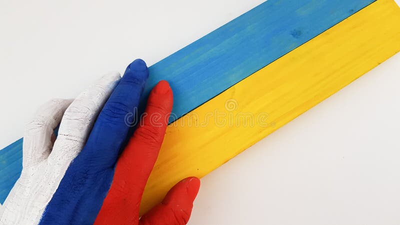 the hand is painted in the colors of the Russian flag and holds the colors of the Ukrainian flag. place for text. the hand is painted in the colors of the Russian flag and holds the colors of the Ukrainian flag. place for text.