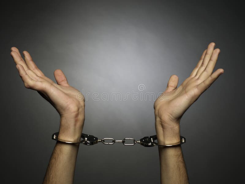 A man hands with handcuffs isolated on black background. A man hands with handcuffs isolated on black background.