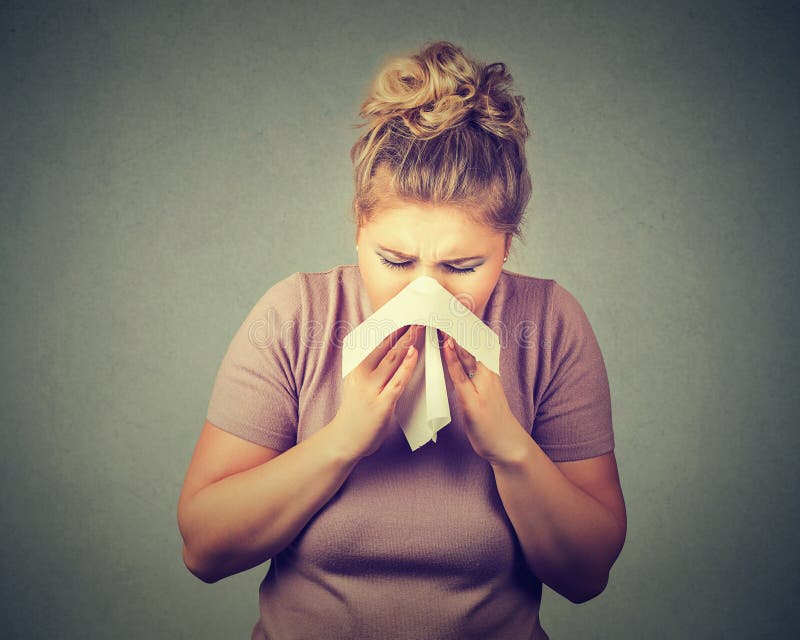 Woman sneezing in a tissue blowing her runny nose. Woman sneezing in a tissue blowing her runny nose