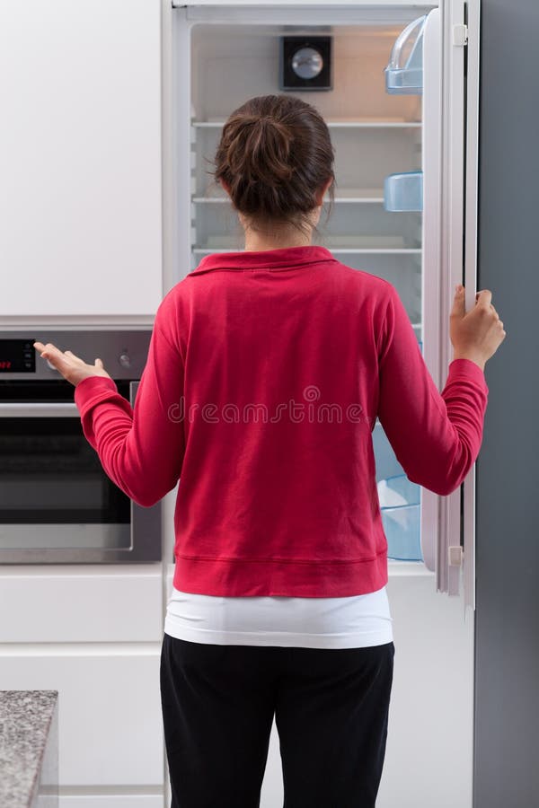 Girl in tracksuit opening the empty refrigerator. Girl in tracksuit opening the empty refrigerator