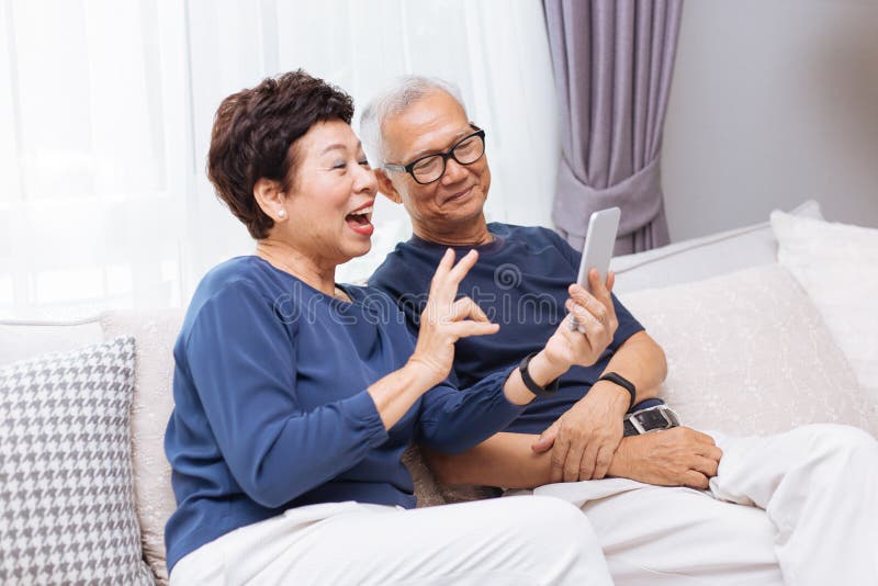 打录影电话和挥动在访问者的资深亚裔夫妇祖父母 库存图片