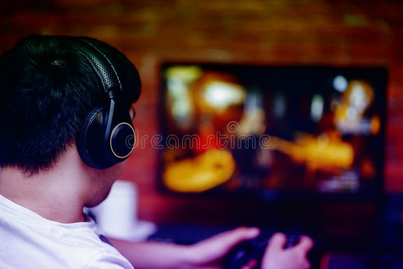 技术、赌博、娱乐、戏剧和人耳机的概念年轻人有打电脑游戏的控制器gamepad的在