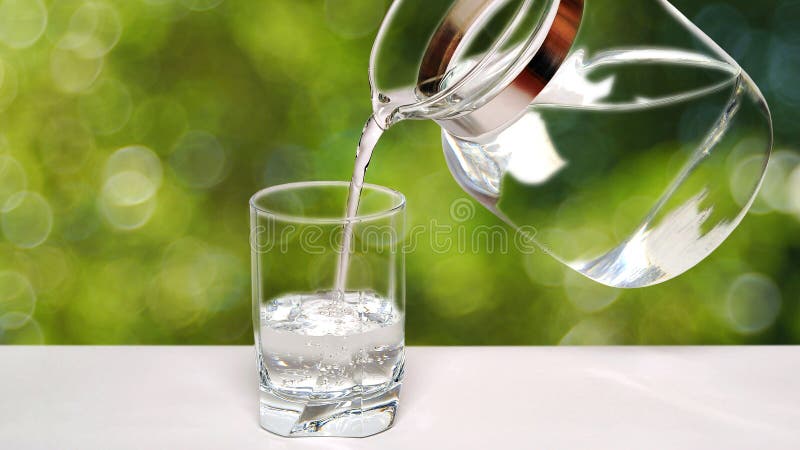 Pouring fresh, drinking, mineral water from the jug into a glass, on a bokeh bubble background. Pouring fresh, drinking, mineral water from the jug into a glass, on a bokeh bubble background