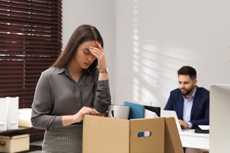 Dismissed woman packing personal stuff into box. Dismissed woman packing personal stuff into box