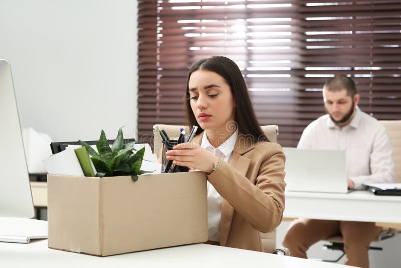 Dismissed women packing personal stuff into box in. Dismissed women packing personal stuff into box in