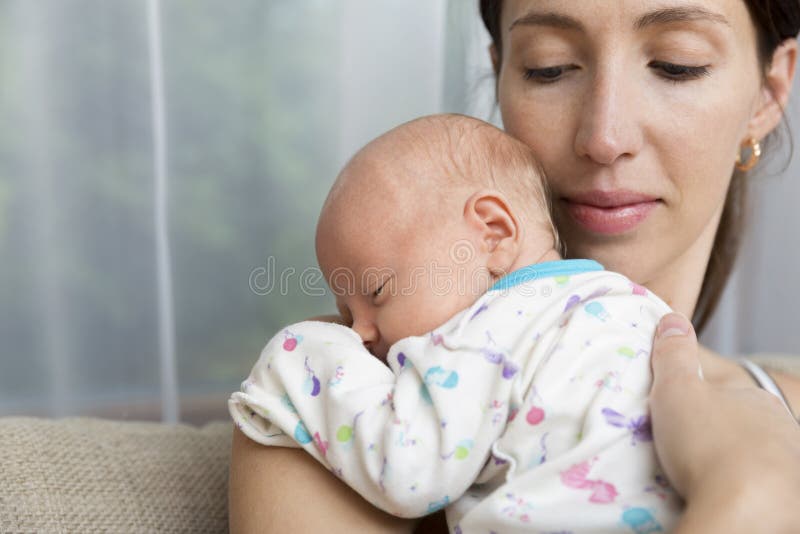 Pretty women holding a newborn baby in her arms in natural light. Pretty women holding a newborn baby in her arms in natural light