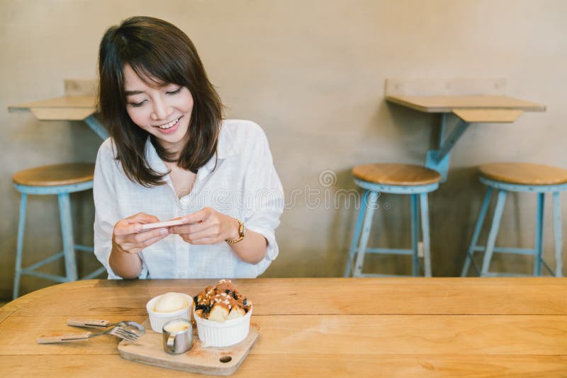 拍巧克力多士蛋糕、冰淇凌和牛奶的照片美丽的亚裔女孩在咖啡店 点心或食物照片爱好 库存照片 拍巧克力多士蛋糕、冰淇凌和牛奶的照片美丽的亚裔女孩在咖啡店 点心或食物照片爱好 库存照片