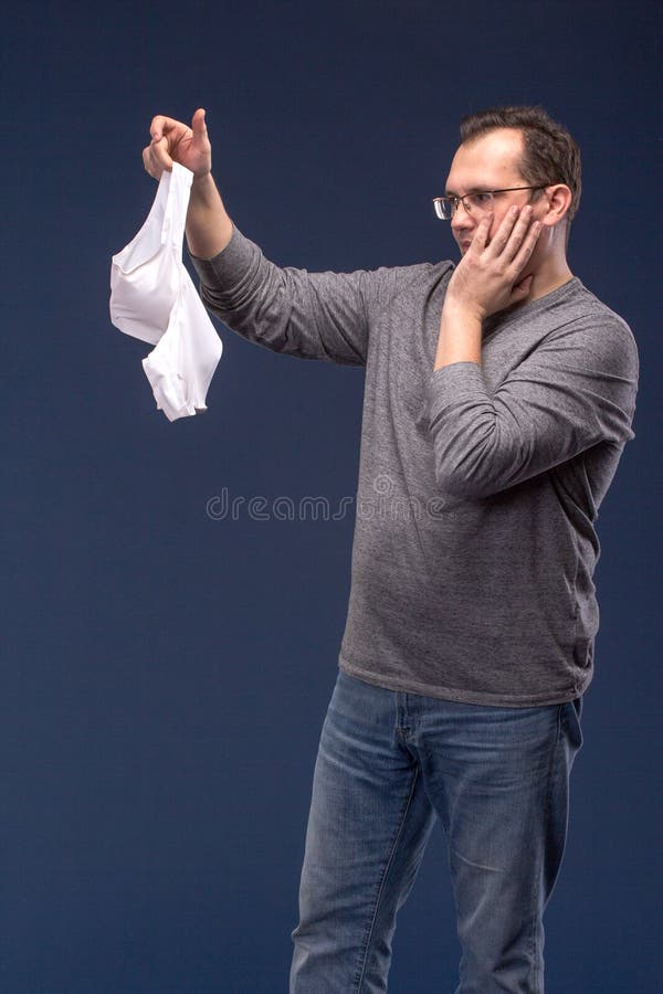 Shocked Man holding a woman`s bra on blue background. Shocked Man holding a woman`s bra on blue background.