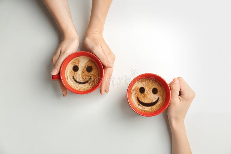 Women holding cups of delicious hot coffee with foam and smiles on light background, top view. Happy morning, good mood, inspiration. Women holding cups of delicious hot coffee with foam and smiles on light background, top view. Happy morning, good mood, inspiration