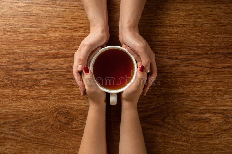 拿着热的茶在木桌上的妇女和人 免版税库存图片 拿着热的茶在木桌上的妇女和人 免版税库存图片