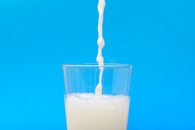 Milk when inflowing into the jar with blue background. Milk when inflowing into the jar with blue background