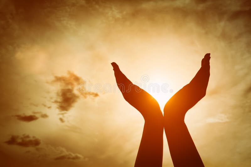 Raised hands catching sun on sunset sky. Concept of spirituality, wellbeing, positive energy etc. Raised hands catching sun on sunset sky. Concept of spirituality, wellbeing, positive energy etc.