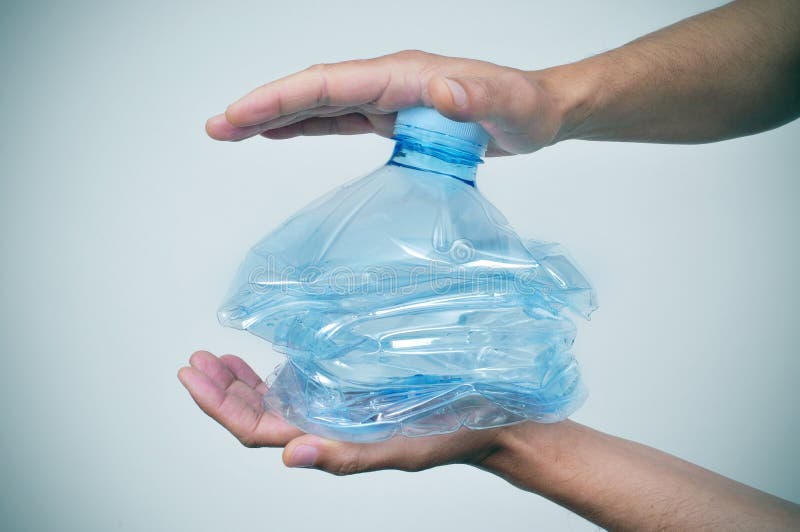 Closeup of a young caucasian man smashing a plastic bottle with his hands. Closeup of a young caucasian man smashing a plastic bottle with his hands