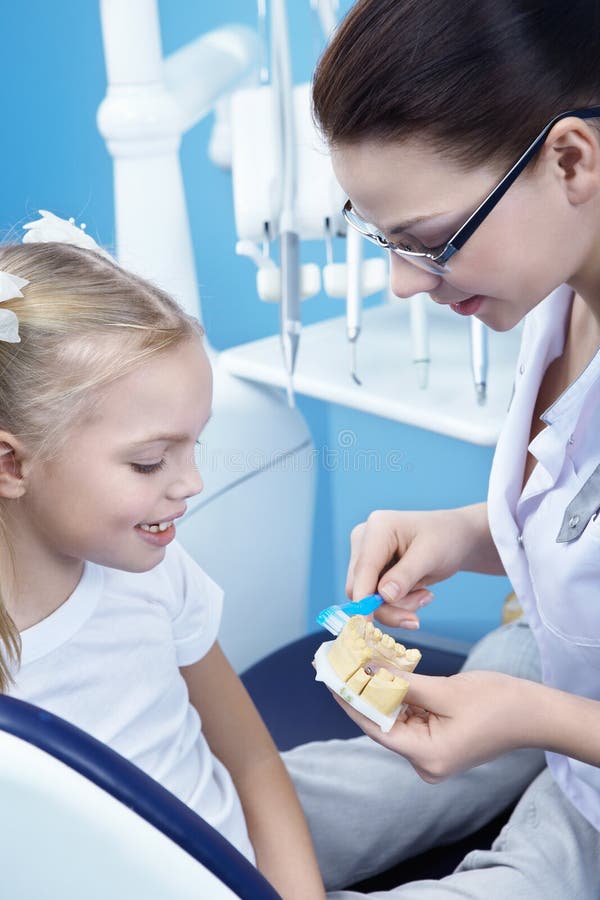 A young dentist shows a child how to brush their teeth. A young dentist shows a child how to brush their teeth